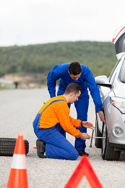 two auto mechanic change a tyre on road.